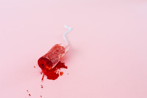 Free Close-up image of a blood-stained tampon on a pink background symbolizing menstruation. Stock Photo