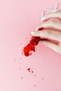 Person Holding Red Liquid on Pink Surface