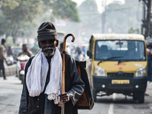 Free Senior man with a walking stick on a busy street in India, showcasing daily life. Stock Photo