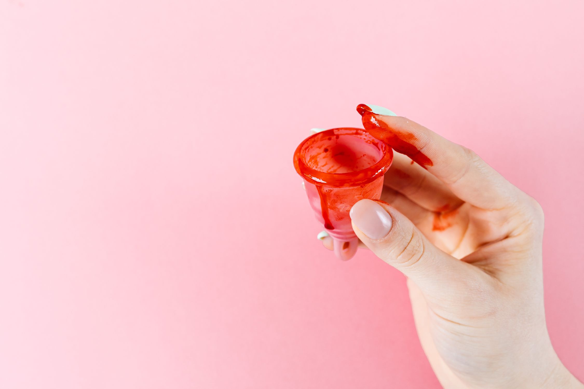Mão segurando coletor menstrual, representando a transição para a maturidade e cuidado com a saúde íntima.