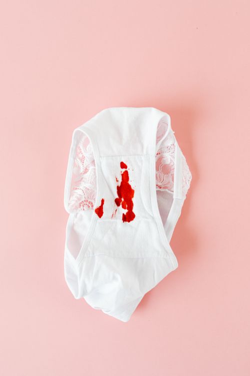 Free Close-up of white underwear with visible menstrual stain on a pastel pink surface, emphasizing menstruation awareness. Stock Photo