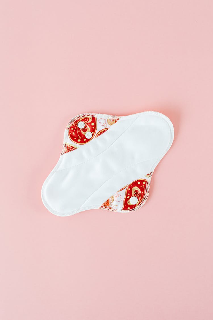 A White Reusable Menstrual Pad On Pink Surface