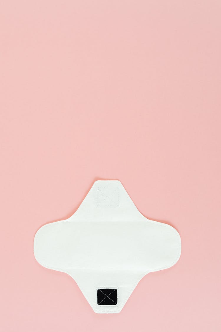 A White Reusable Menstrual Pad On Pink Surface