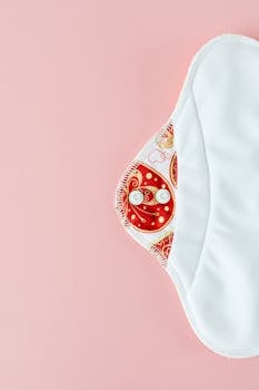 Eco-friendly reusable menstrual pad on soft pink background promoting zero waste.