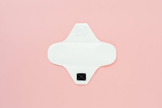 Reusable menstrual pad on a pink surface promoting zero waste living.