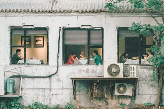 View of cafe customers enjoying meals through rustic vintage windows of a building.