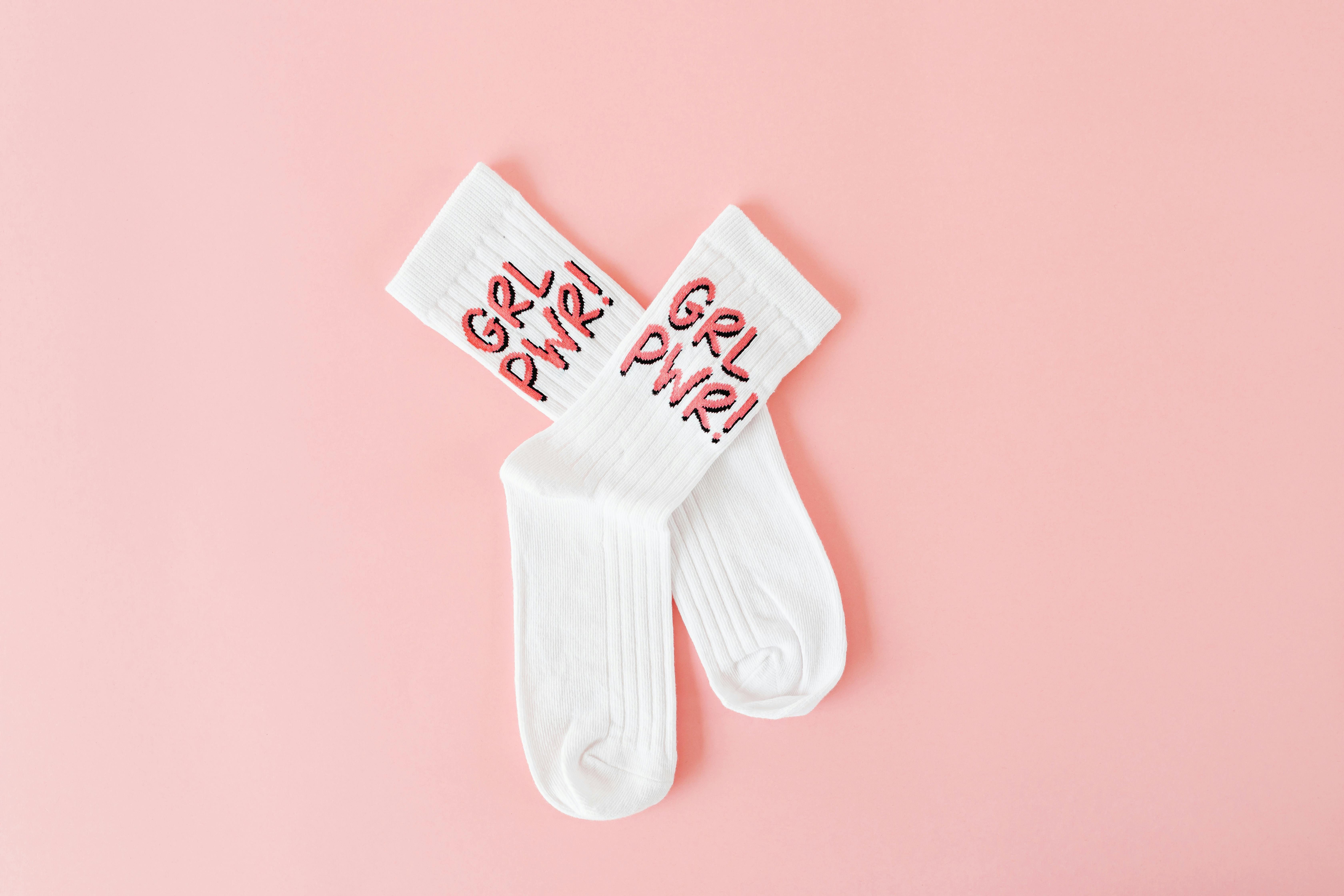 White socks embroidered with 'Grl Pwr' on a pink background, symbolizing empowerment.
