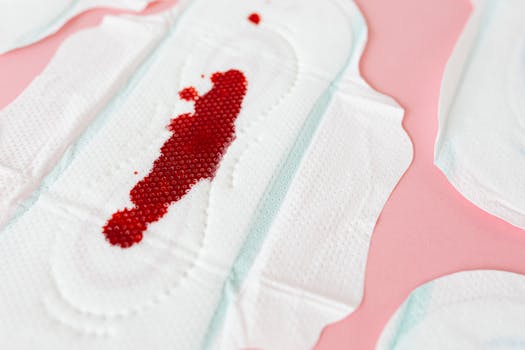 Close-up of a menstrual pad with blood on a pink surface, highlighting feminine care.