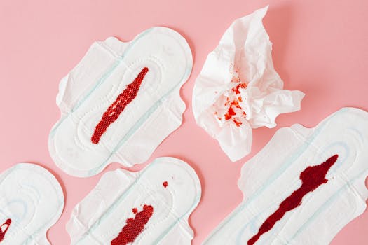 Close-up of menstrual pads with blood and tissue on a pink surface, highlighting menstruation.