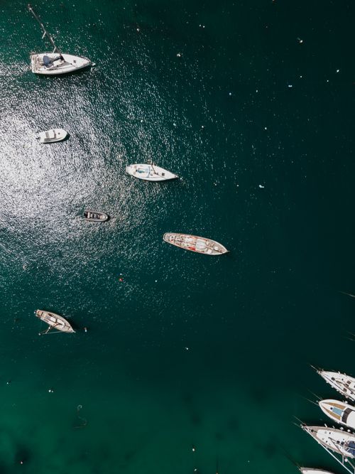 Free Drone shot capturing the serene beauty of boats floating in the clear waters of Kalkara, Malta. Stock Photo