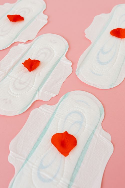 Free Top view of sanitary pads with red petals on a pink background, symbolizing menstrual care. Stock Photo