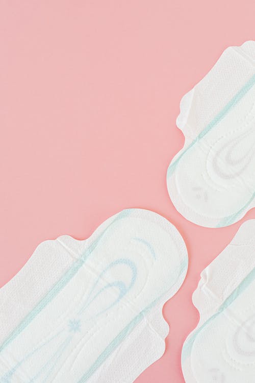 White and Blue Sanitary Napkins on Pink Surface