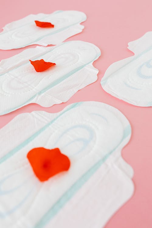White Sanitary Pads with Red Petals on Pink Surface