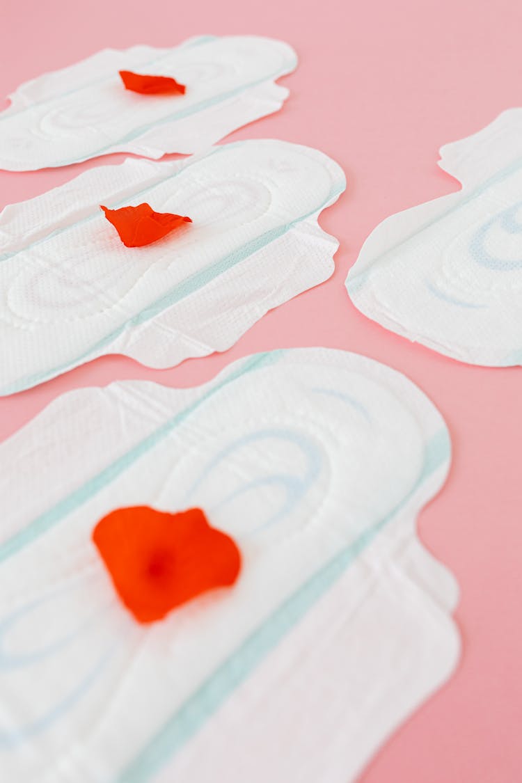 White Sanitary Pads With Red Petals On Pink Surface