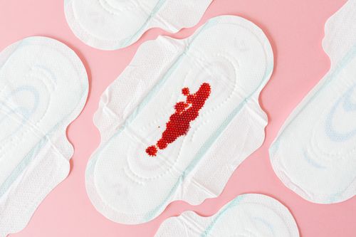 Free Flat lay of sanitary pads with red beads on pink surface, highlighting menstrual health. Stock Photo