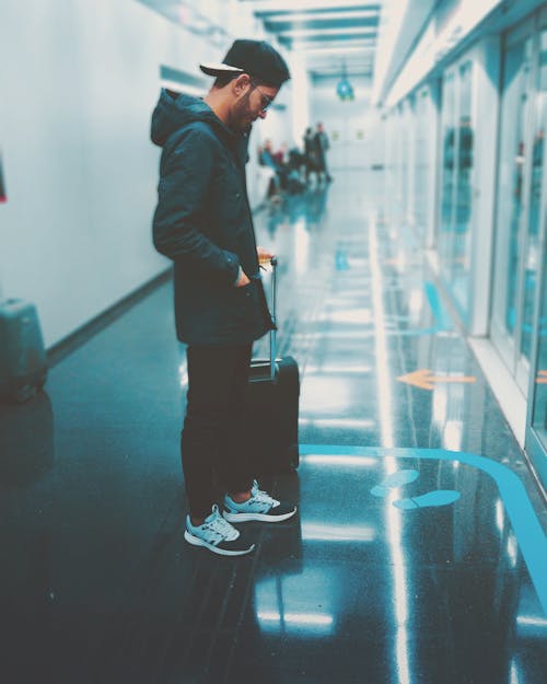 男子拿著行李站在玻璃面板的前面