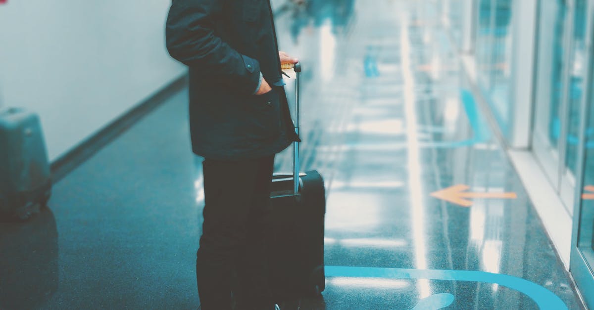Man Stands Front of Glass Panel While Holding Luggage