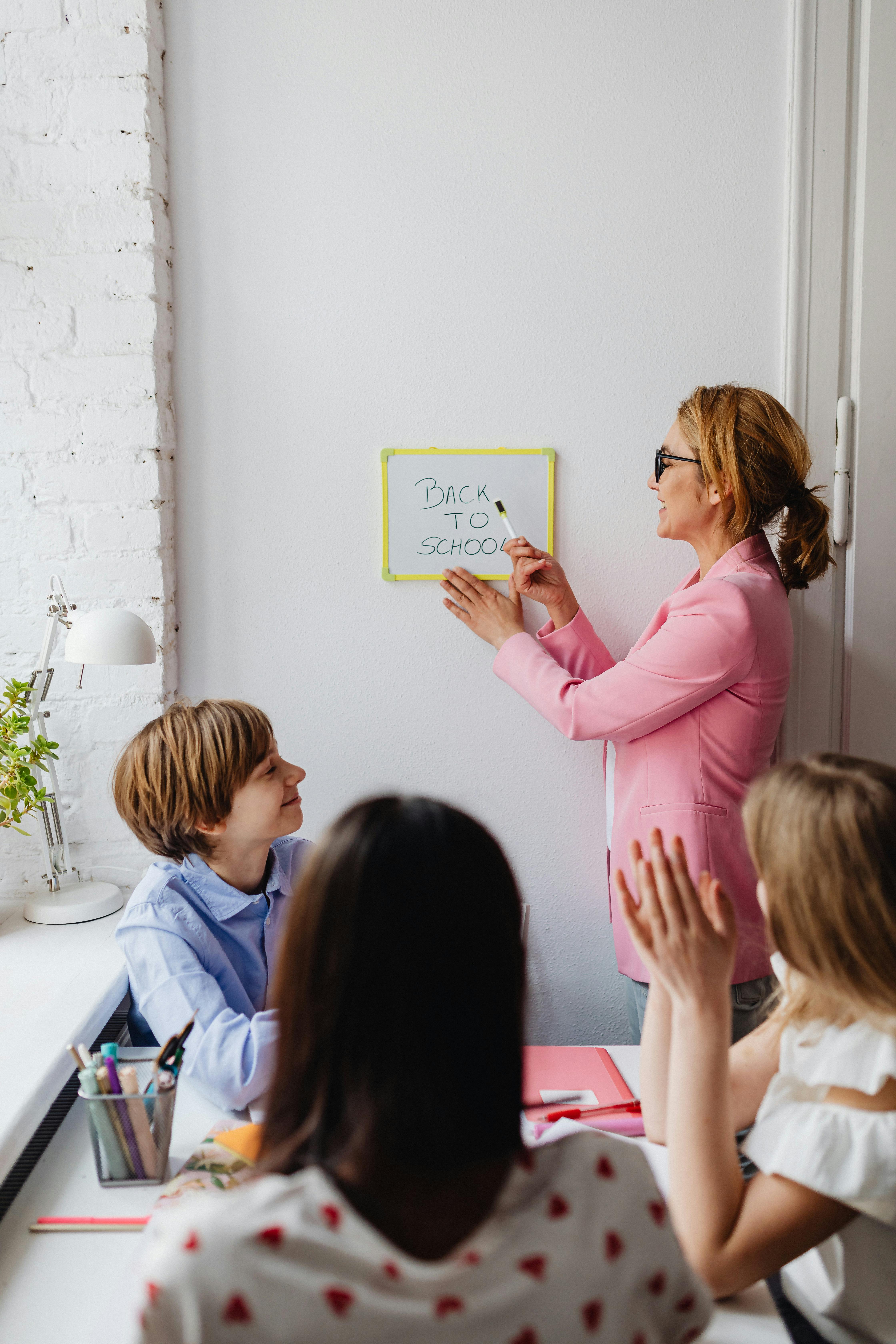 teacher showing a whiteboard with back to school text to her students