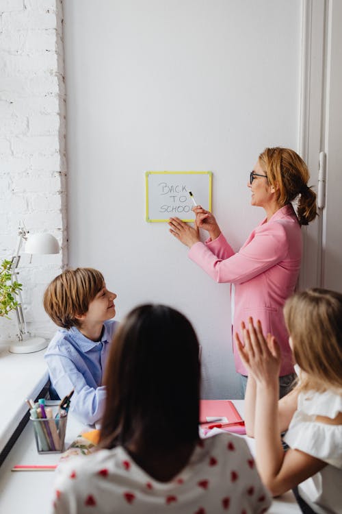 Free Teacher Showing a Whiteboard with Back to School Text to Her Students Stock Photo