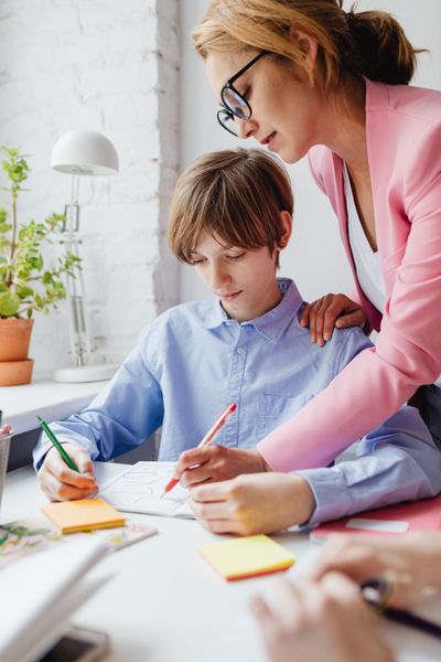 A teacher helping a student with homework at a desk — photo by Kaboompics on Pexels
