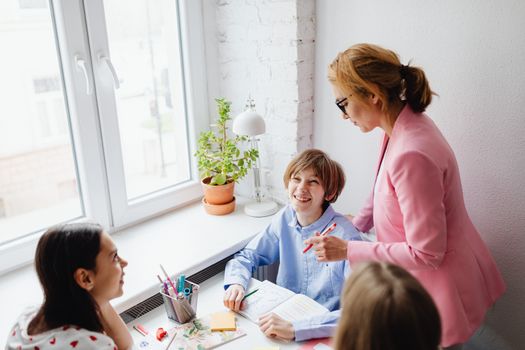 A teacher guides students in a bright, collaborative classroom environment.