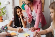 Woman in Pink Blazer Holding Pen Writing on White Paper