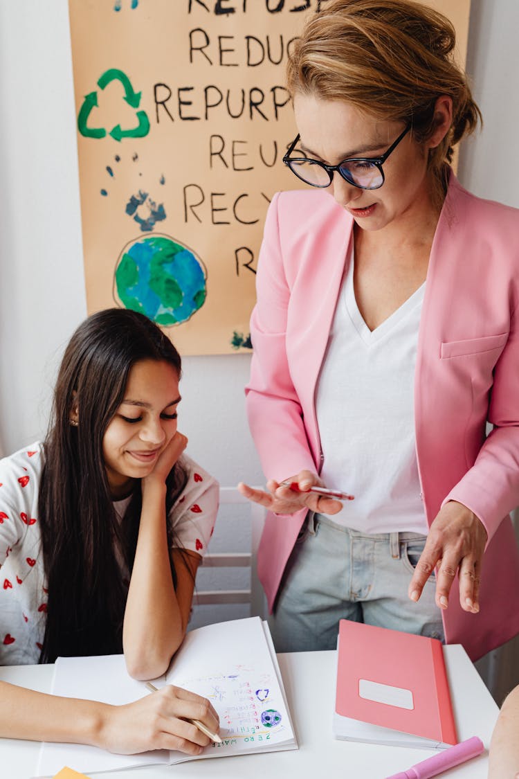 A Woman Teaching A Young Student At School