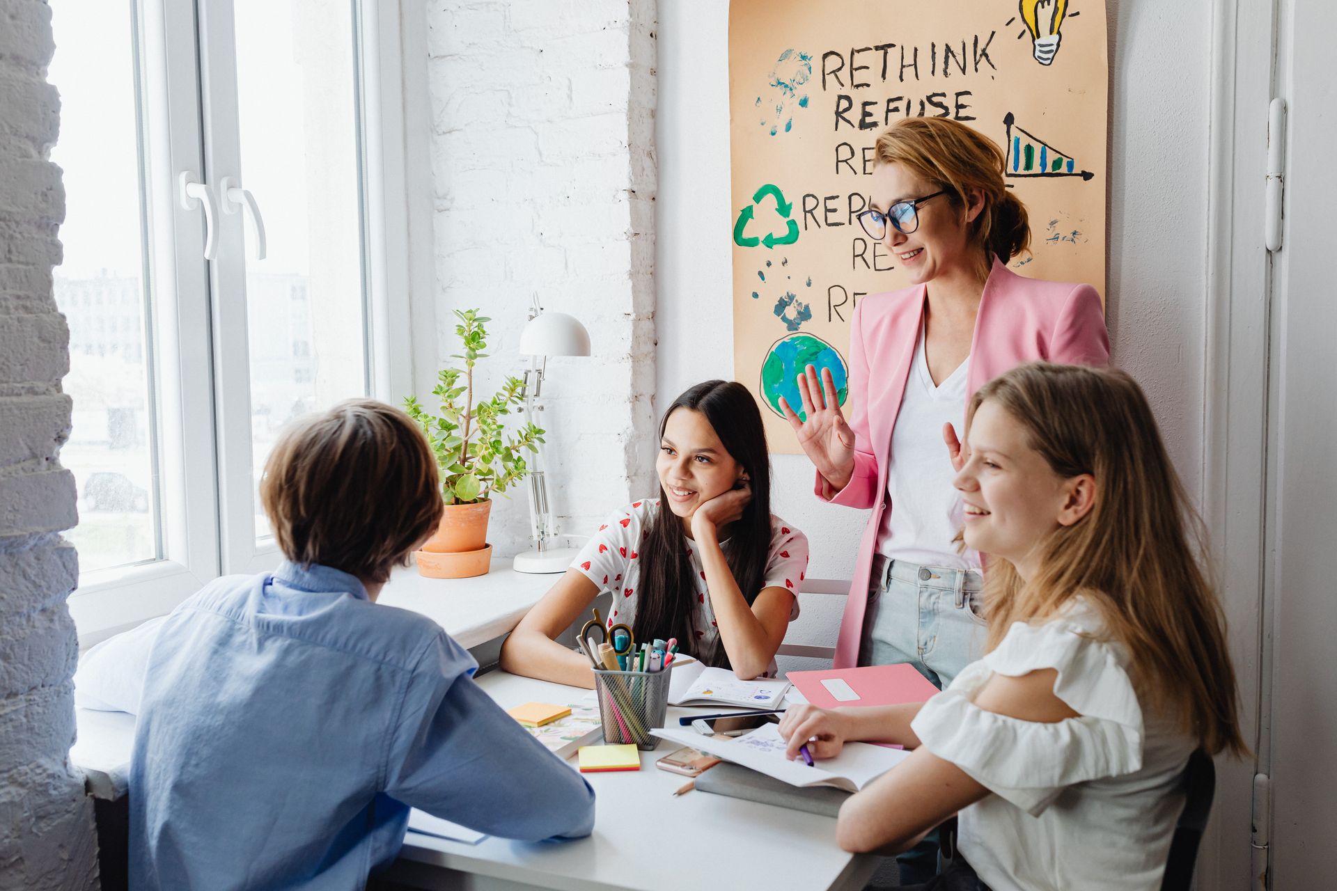 A teacher engages with students in a bright classroom setting, fostering creativity and discussion.
