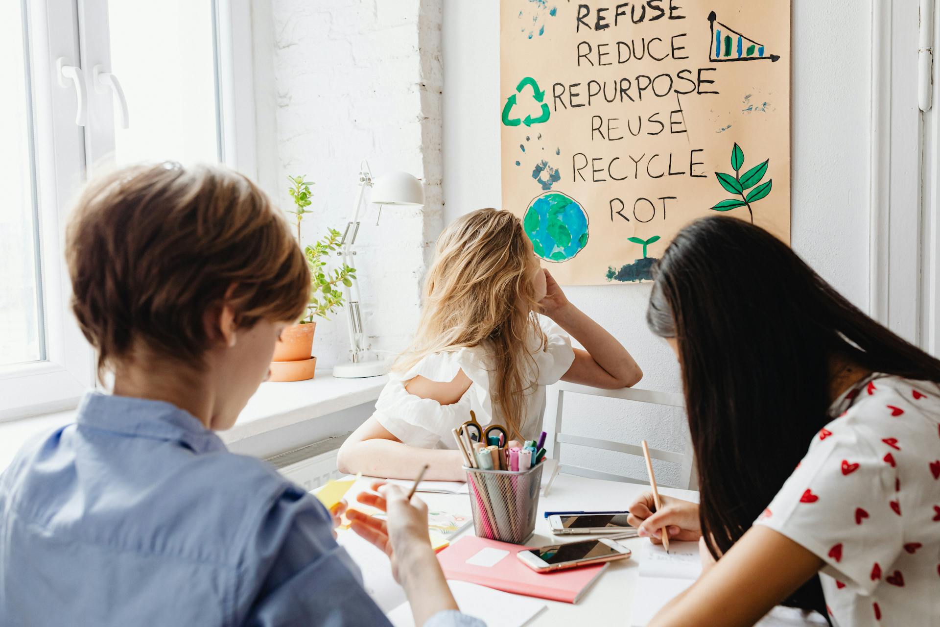 Three teenagers working together on an environmental project with a focus on sustainability indoors.