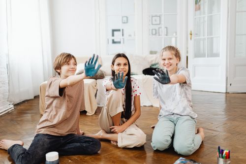 Free Three smiling teenagers showing painted hands enjoying a creative activity indoors. Stock Photo