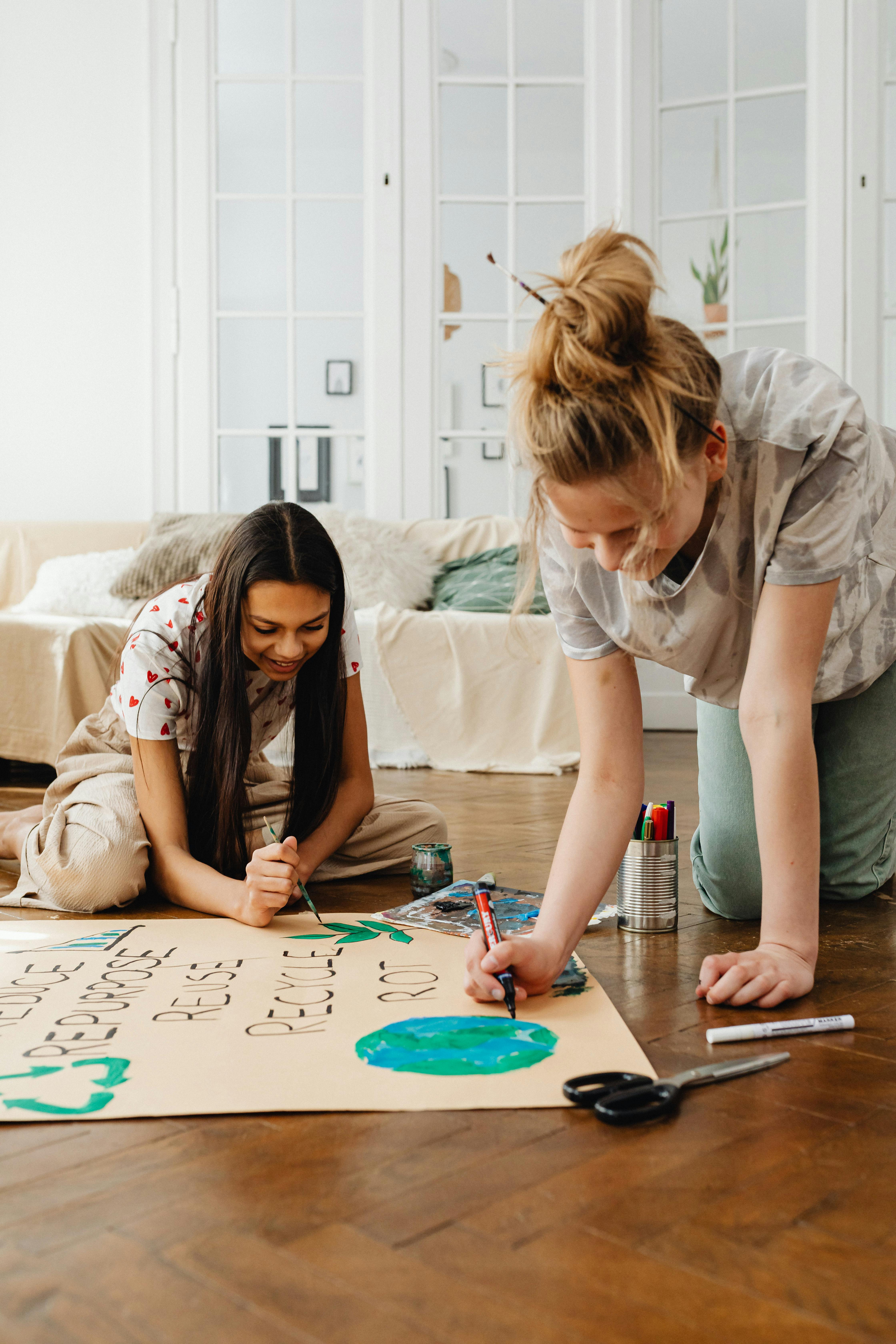 women painting on brown paper on the floor