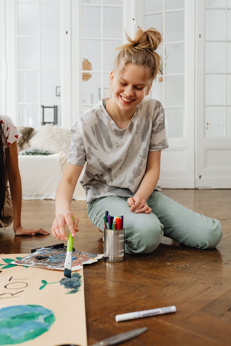 Smiling Blonde Girl Sitting And Painting