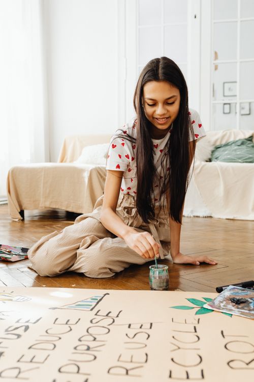 Free Young girl creating environmentally themed art project in cozy indoor setting. Stock Photo