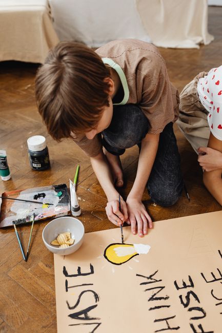 A child engaged in a school project painting with eco-friendly messages on a poster. A child engaged in a school project painting with eco-friendly messages on a poster.