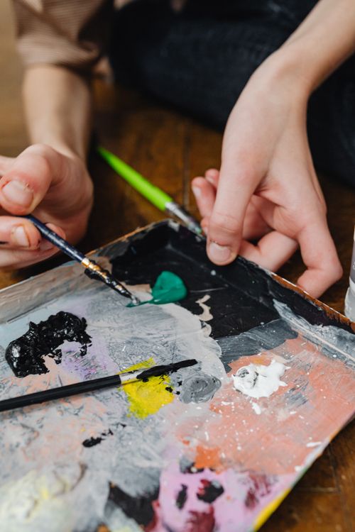 Free Close-up of hands with paintbrush mixing colors on a paint palette. Stock Photo