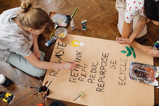 Top view of two young adults crafting an eco-friendly sign emphasizing recycling and repurposing.