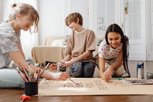 Free Three teenagers enjoy a fun painting session indoors, fostering creativity and friendship. Stock Photo