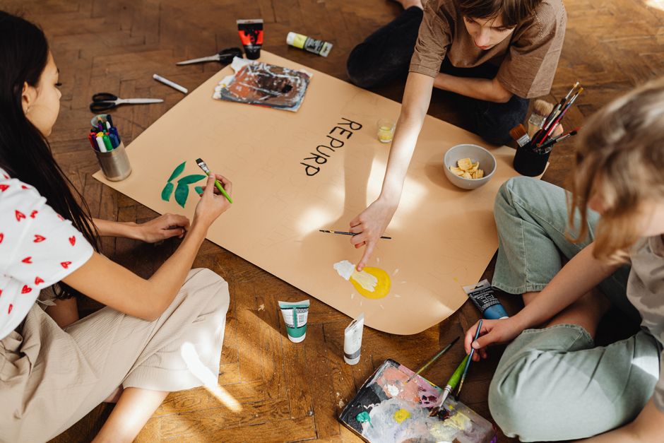 Como a Criatividade Pode Transformar seu Estilo de Vida Sustentável 2 Group of teenagers working on an artistic project indoors with art supplies.