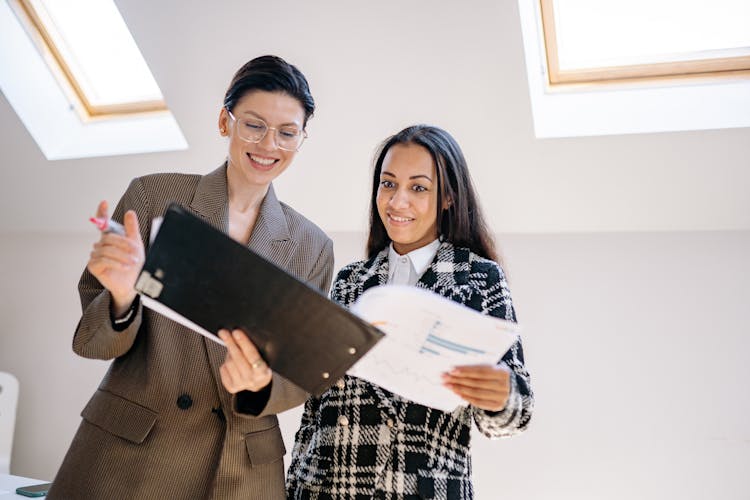 Happy Women In Corporate Attire Looking At A Document