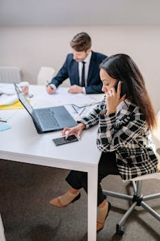 Two business professionals collaborating on a project in a modern office environment.