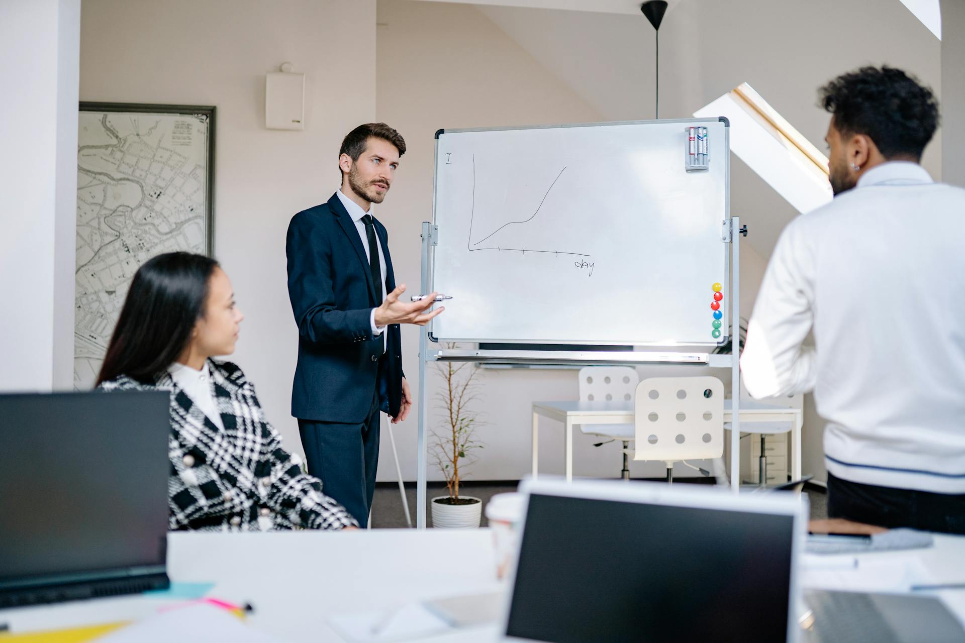 Business team in office presenting growth graph on a whiteboard for strategy discussion and teamwork insights.