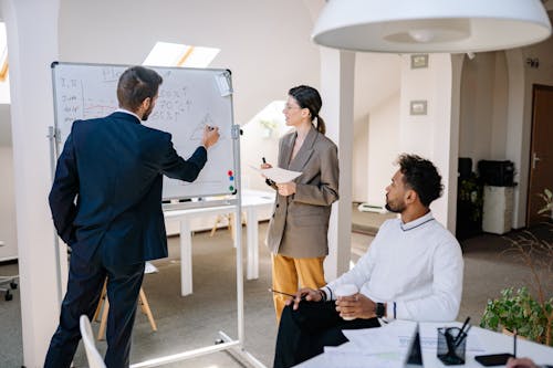 A Man in Blue Suit Jacket Writing on the Whiteboard