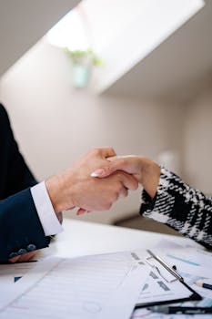 Close-up of a professional handshake between colleagues in a modern office setting, symbolizing agreement.