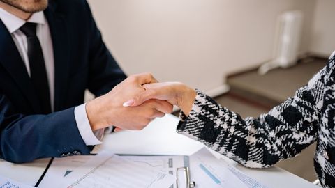 Apretón de manos sobre documentos durante una negociación de negocios