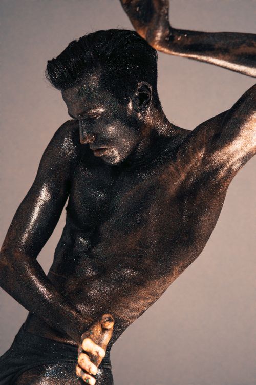 Free Artistic photo of a glitter-covered male model posing in a studio. Stock Photo