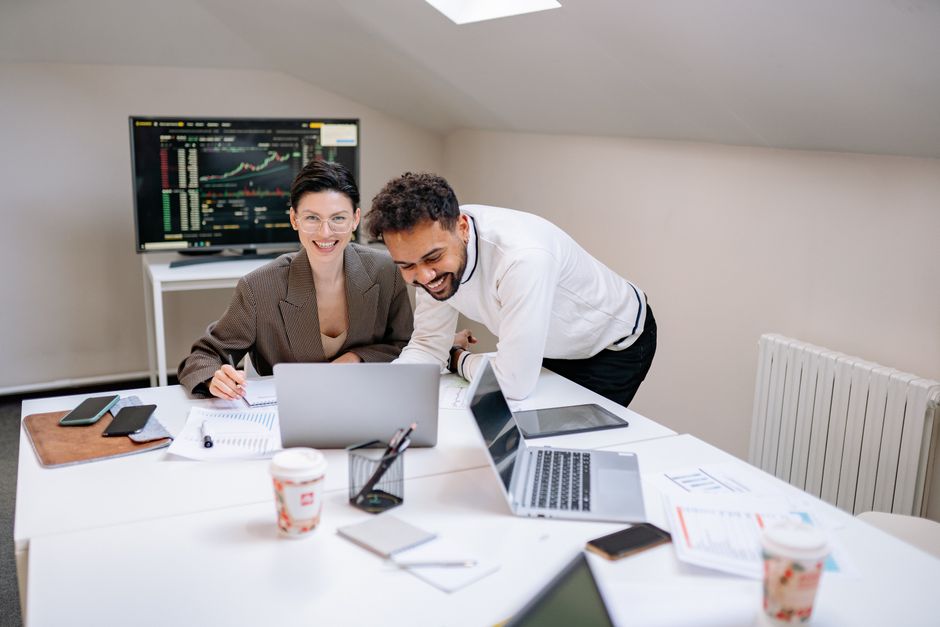 Happy couple looking at a laptop, comparing mortgage rates on a website with charts and numbers