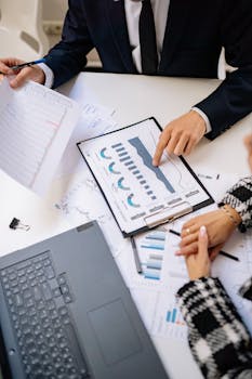 Teamwork in a modern office setting with charts and laptops showcasing collaboration.