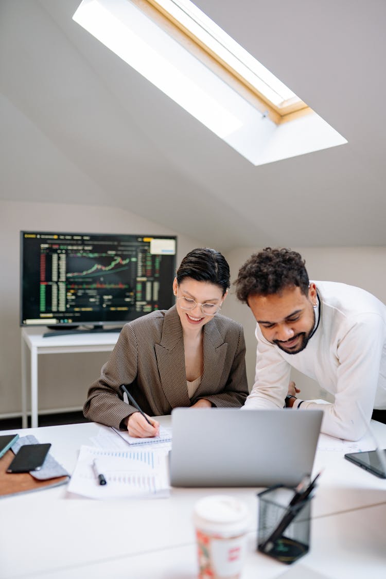 A Man And A Woman Smiling While Working At An Office