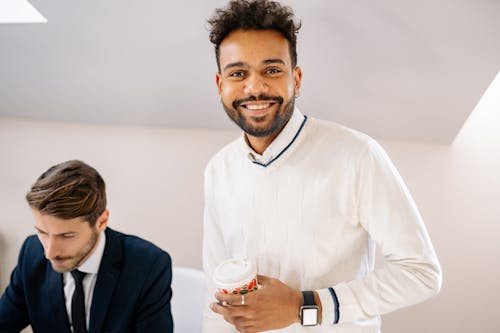 A Bearded Man in White Sweater Holding a Cup of Coffee