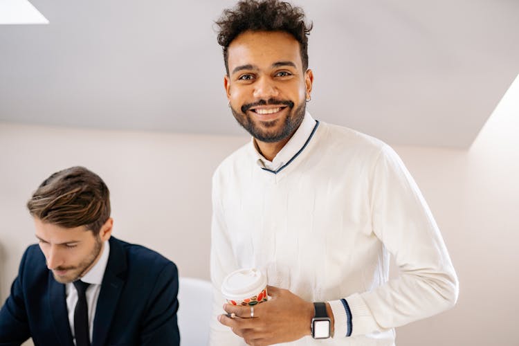 A Bearded Man In White Sweater Holding A Cup Of Coffee